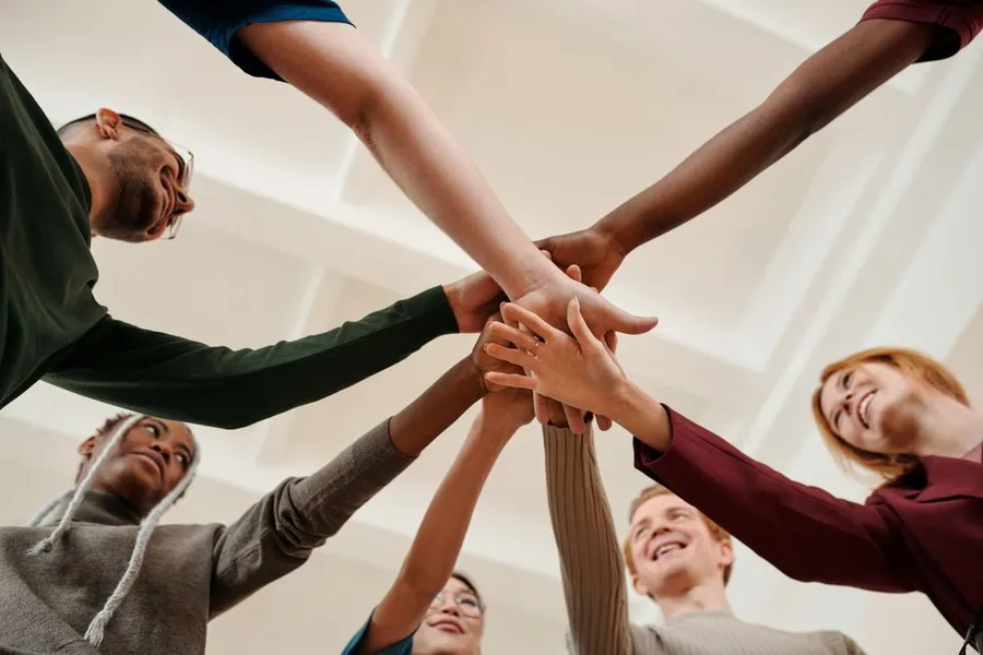 Young people in a circle with their hands together