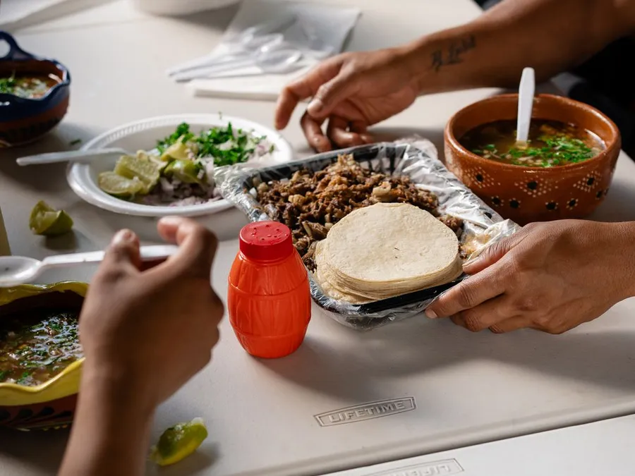 Hands reaching for a shared spread of tacos